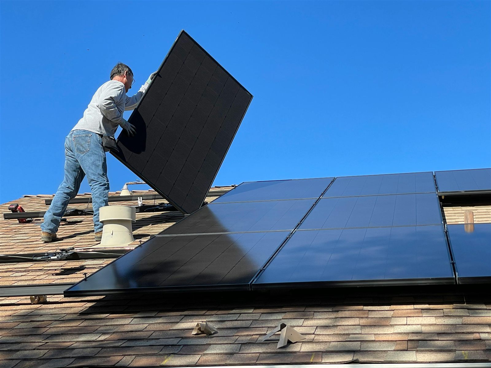 Technician performing solar panel removal and reinstall work on a residential roof